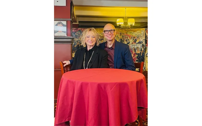 Judy Craymer sitting on a table with a red table cloth